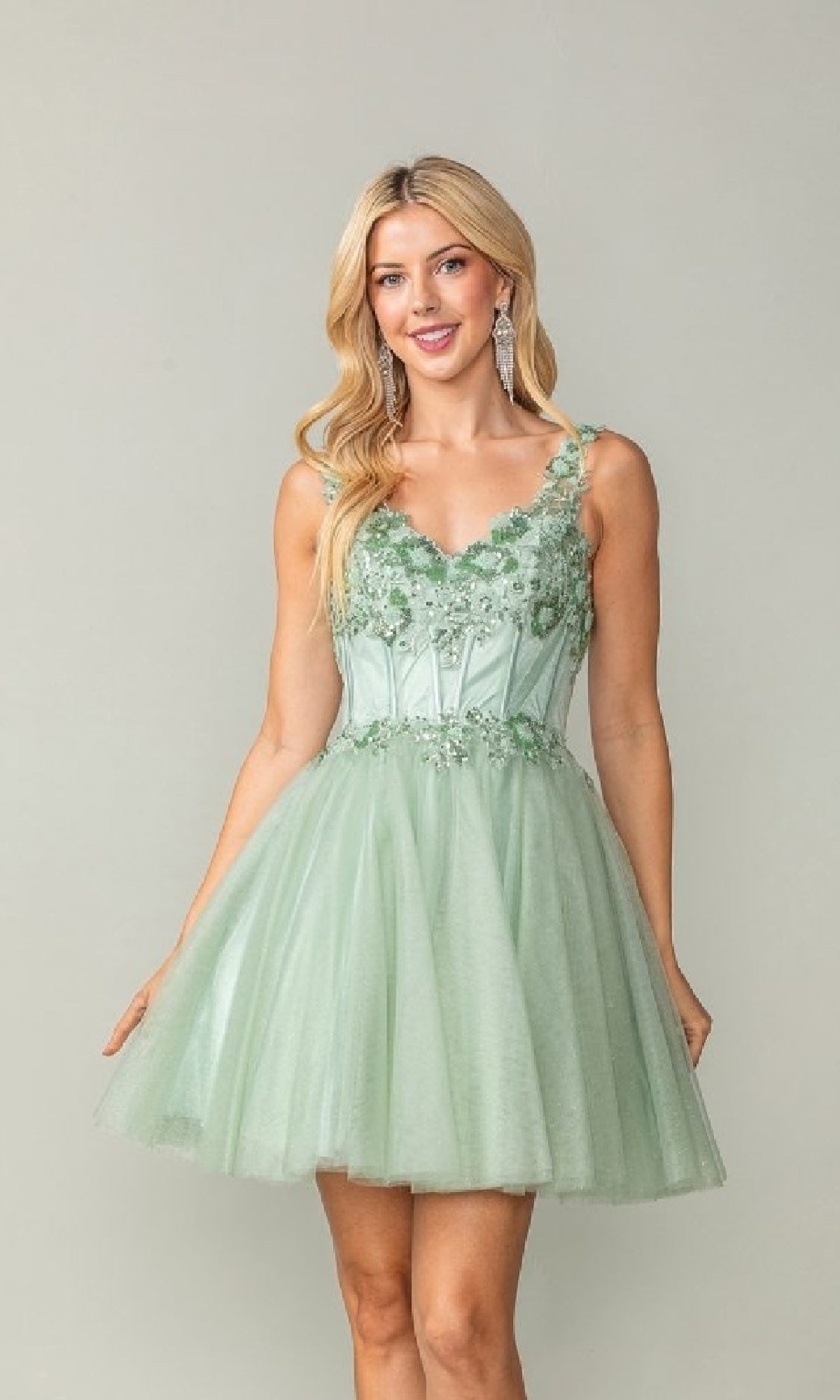 Woman wearing a light green short dress with lace details on a plain background